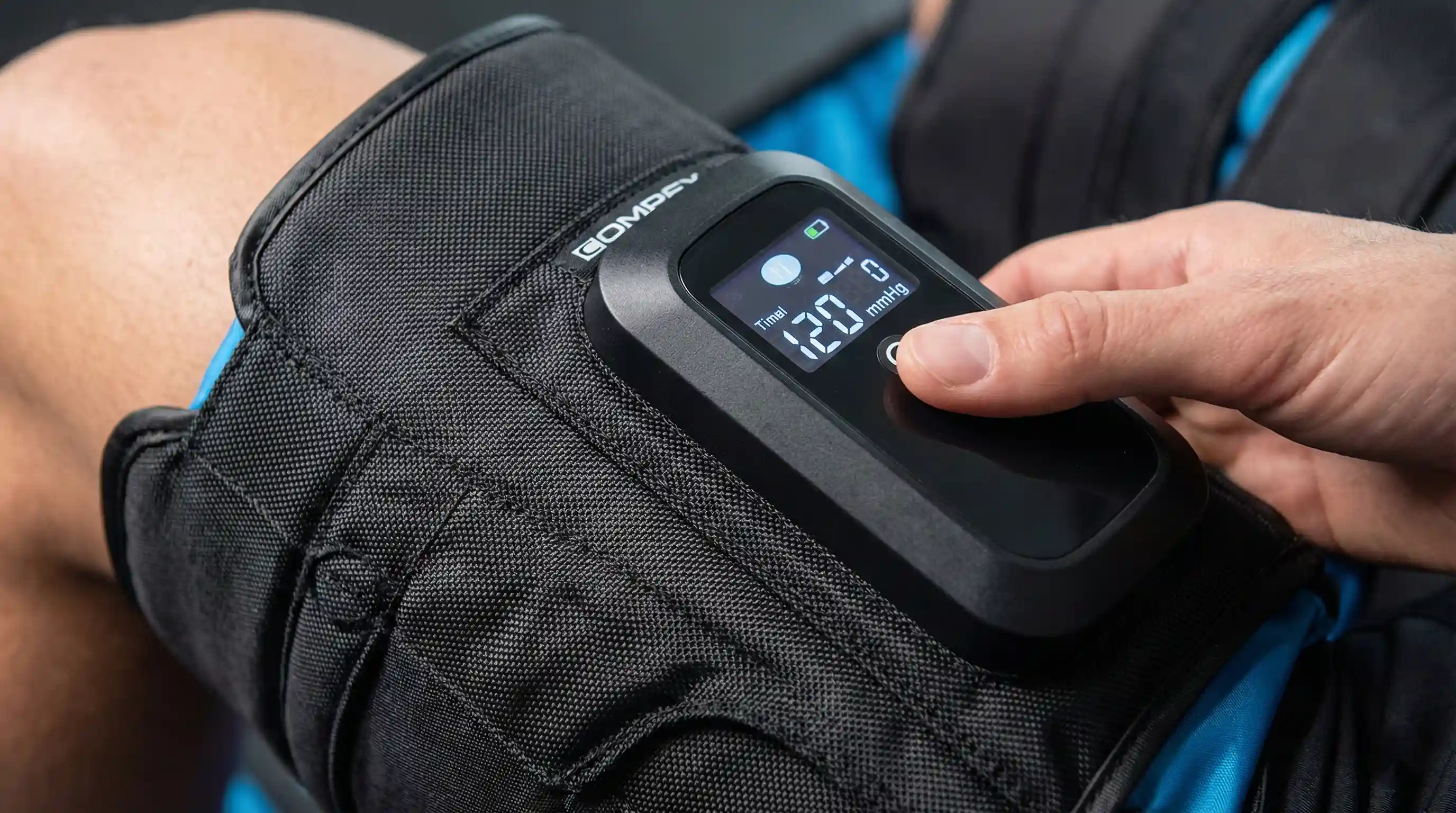 Primer plano de las botas de presoterapia Compex Ayre mostrando el panel de control digital LCD integrado en el muslo y la textura de nailon balístico de alta resistencia