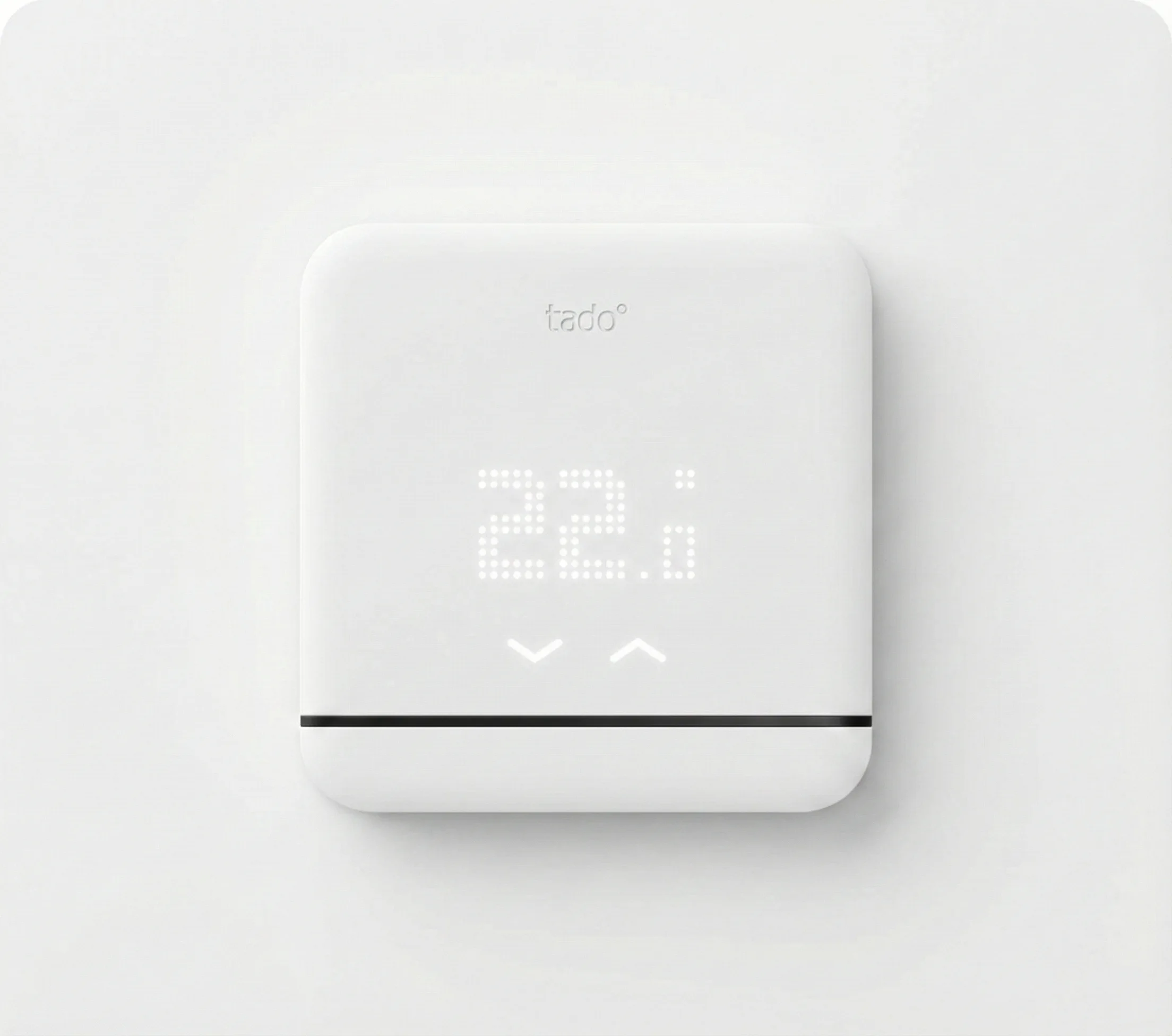 Detalle de un tado° Mando Inteligente instalado en una pared blanca de diseño minimalista mostrando la temperatura digital LED