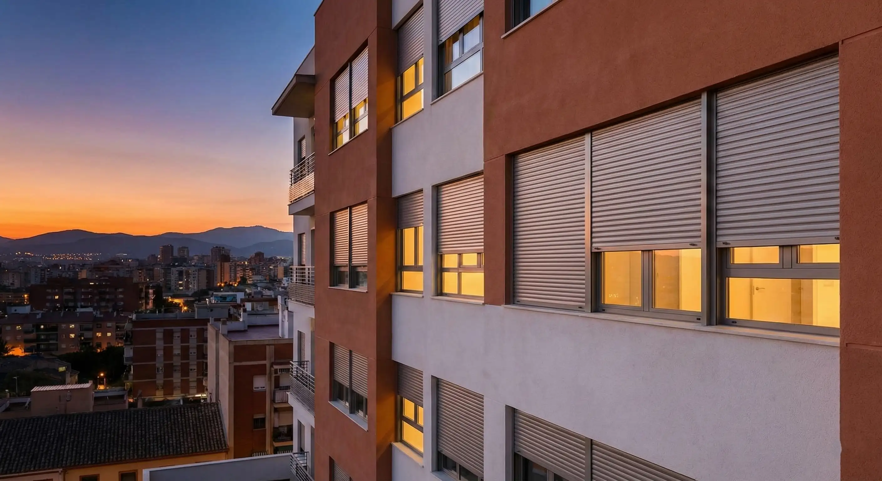 Persianas de lamas de aluminio automáticas bajando de forma sincronizada en un salón moderno durante el atardecer para mejorar el aislamiento térmico