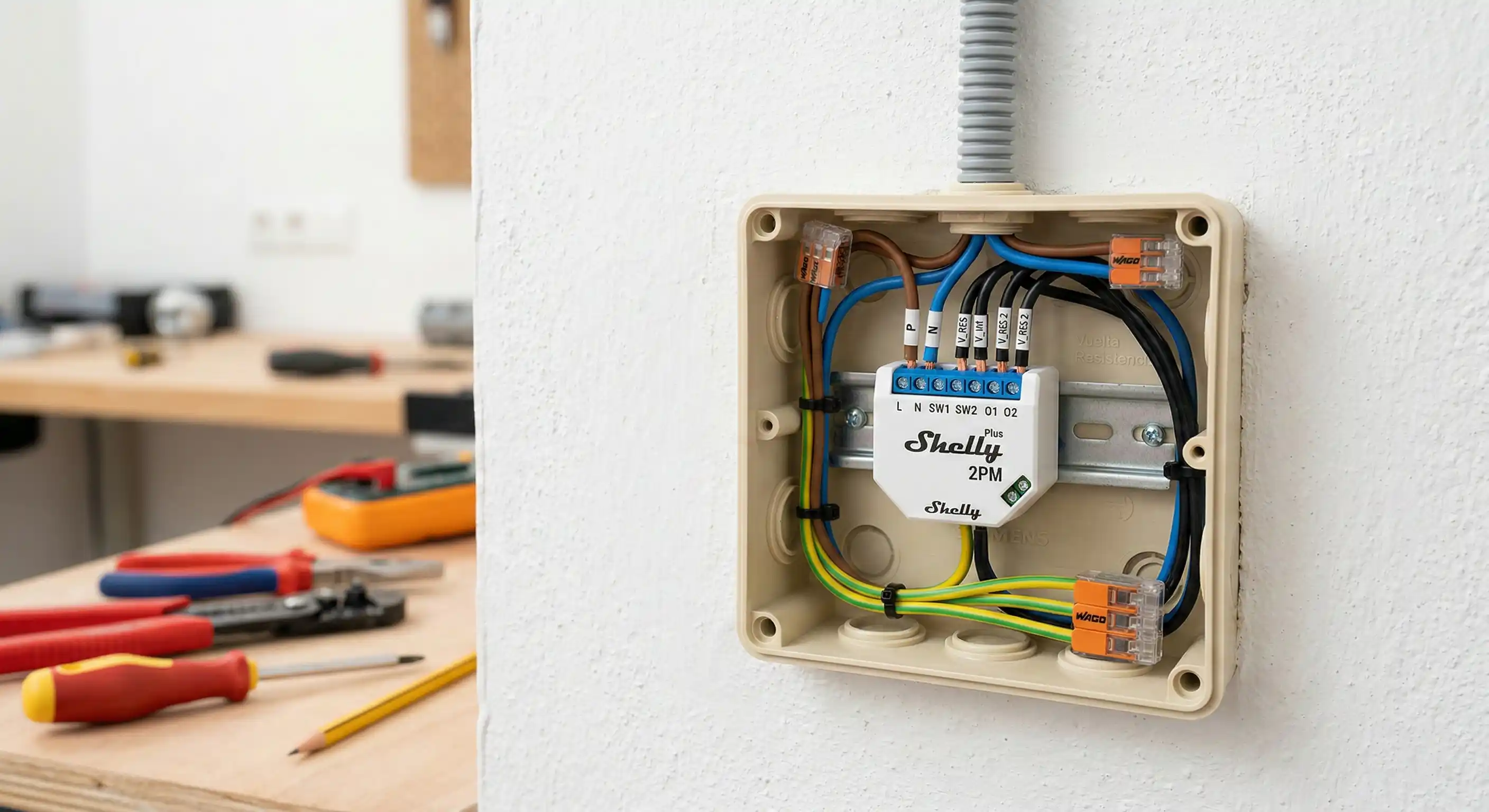 Primer plano de un relé inteligente Shelly Plus 2PM instalado dentro de una caja de derivación estándar española. Iluminación clara de taller que permite distinguir perfectamente los cables azul (neutro), marrón (fase) y negro (vuelta de resistencia). La imagen transmite seguridad eléctrica y un acabado profesional.
